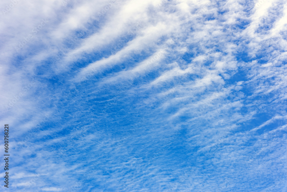 Wavy white clouds spread in the blue sky. Sky background.