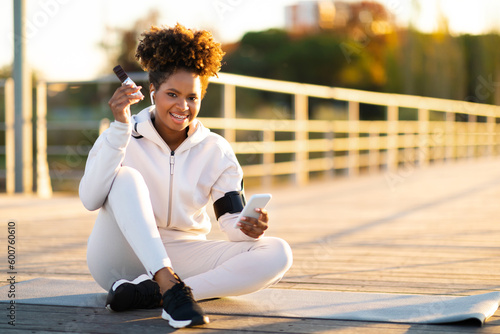 Fitness Snacks. Smiling Black Woman Eating Proteing Bar After Training Outdoors photo