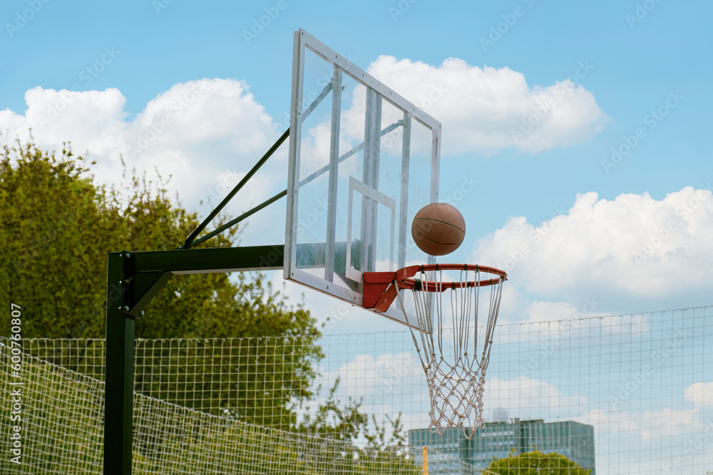 Basketball ball flies into the ring. Outdoor sports ground for playing basketball. Sports activities in city parks. Basketball ball flies into the ring. Outdoor sports ground for playing basketball. Sports activities in city parks.