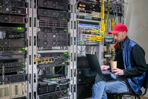 The system administrator works in the server room. A man with a laptop sits on a chair in a data center