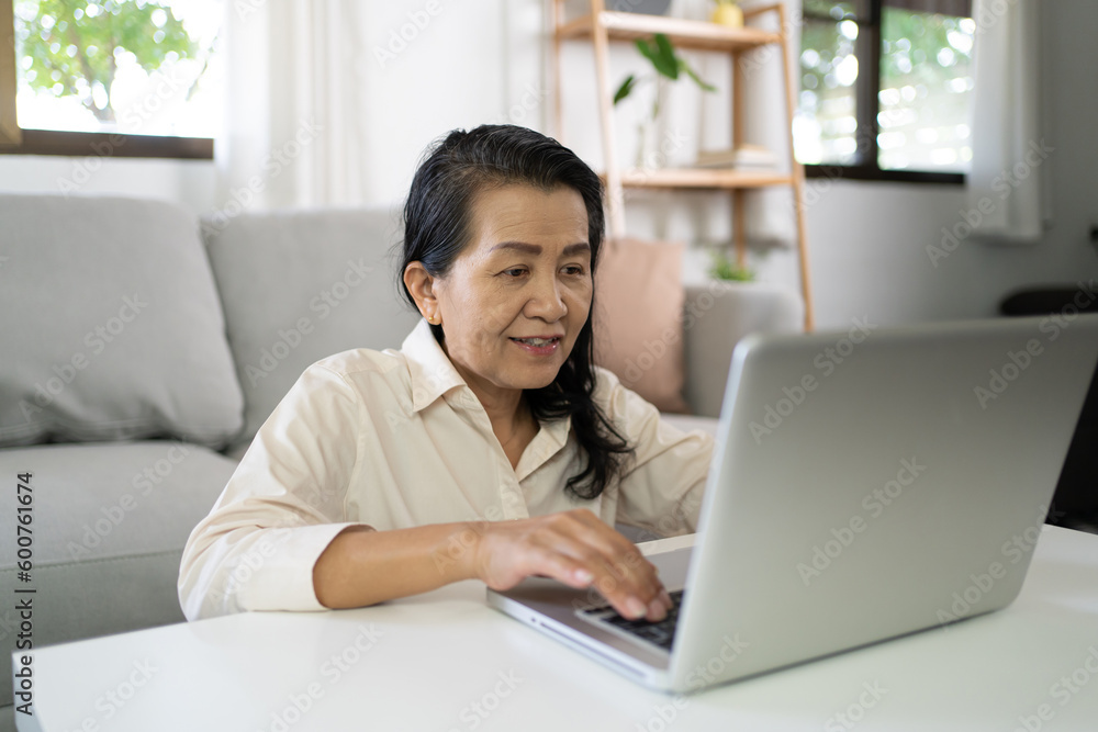 Middle age Asian woman Work from home. senior woman smiling Beautiful mature asian woman on laptop with technology concept Middle age Asian woman Work from home. senior woman smiling Beautiful mature asian woman on laptop with technology concept
