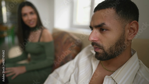Angry muted boyfriend sitting in silence during argument with girlfriend. Upset young man with serious expression feeling annoyed by girlfriend_s nagging