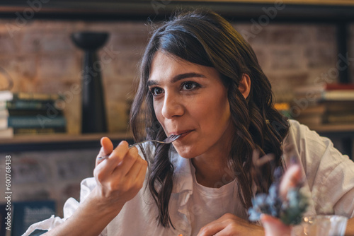 Photography Portrait of a happy young attractive dark-haired woman eating in a cafe