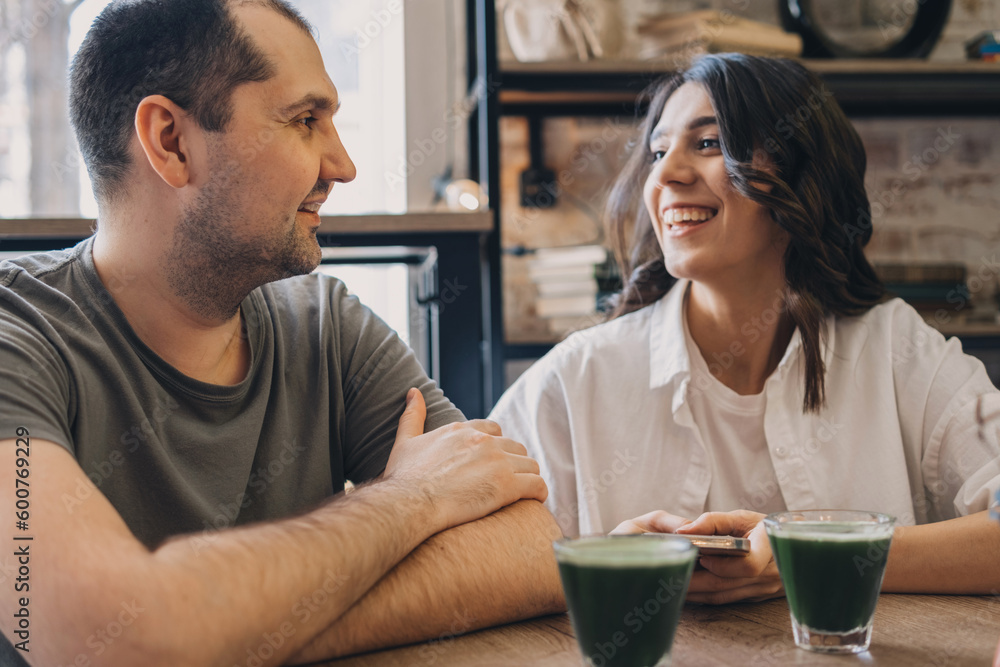 A happy man and a woman are talking in a cafe.Glasses of matcha tea on the table.Communication, healthy eating concept. A happy man and a woman are talking in a cafe.Glasses of matcha tea on the table.Communication, healthy eating concept.