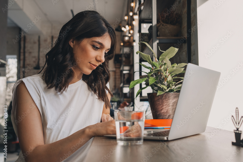Attractive positive young woman using a laptop in a cafe.Remote work,blogging,business, freelance,e-learning. Attractive positive young woman using a laptop in a cafe.Remote work,blogging,business, freelance,e-learning.