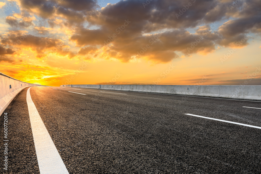 Fototapeta premium Asphalt highway and sky clouds background at sunset