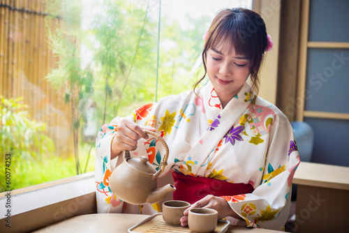 Photography Young woman wearing traditional kimono sitting in a Japanese style house pouring