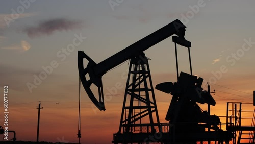 Silhouette of a working oil pump at sunset. Crude oil, industry. Oil field.