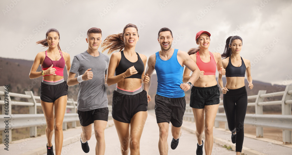 Group of people in sportswear running over a bridge