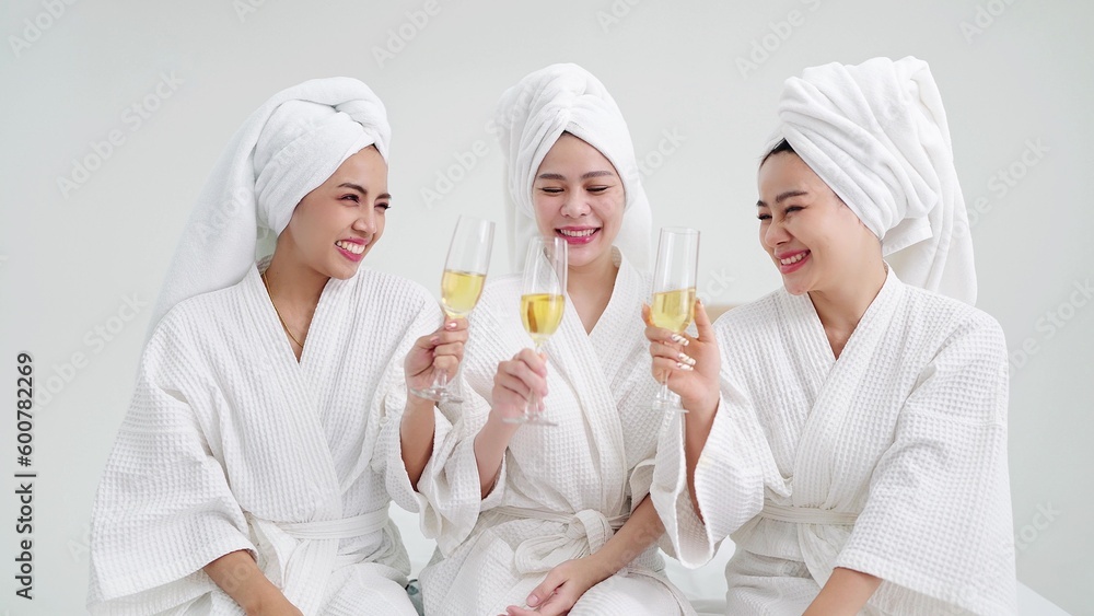 Happy young female friends in bathrobes and towels on heads holding champagne glasses. Friends together concept Happy young female friends in bathrobes and towels on heads holding champagne glasses. Friends together concept
