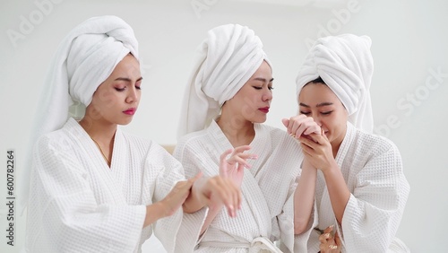 Group of young beautiful Asian woman in white bathrobe enjoy applies moisturizing cream to skin feeling fragrant smell. Skin care concepts