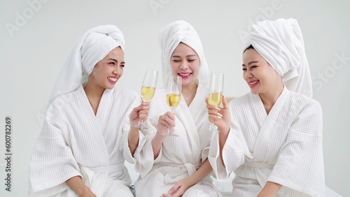 Happy young female friends in bathrobes and towels on heads holding champagne glasses. Friends together concept