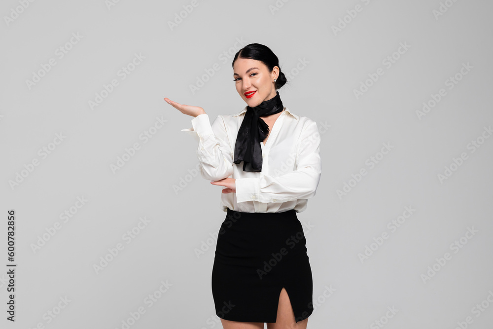 Portrait of an attractive young Stewardess. Charming, smiling air hostess in sensual uniform, demonstrative gesturing. Isolated on white background. Portrait of an attractive young Stewardess. Charming, smiling air hostess in sensual uniform, demonstrative gesturing. Isolated on white background.