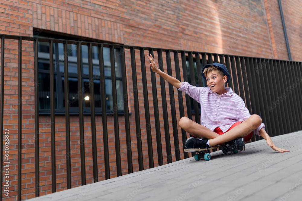 Caucasian boy sitting in skateboard and going down the hill, looking at camera. Caucasian boy sitting in skateboard and going down the hill, looking at camera.