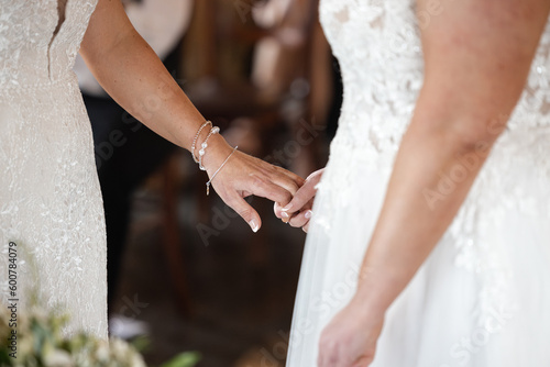 Beautiful two brides at same sex couple wedding ceremony holding hands in white dresses. Romantic, intimate and full of love.