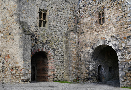 Worn old  stone walls of ruined medieval buildings with arch leading to dark passage