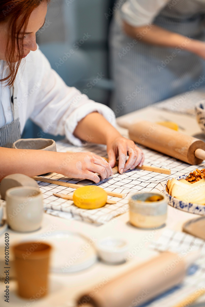 Crop woman making clay stripe with wooden sticks Crop woman making clay stripe with wooden sticks