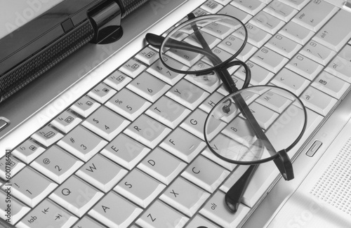 Round eyeglasses on silver laptop keyboard 