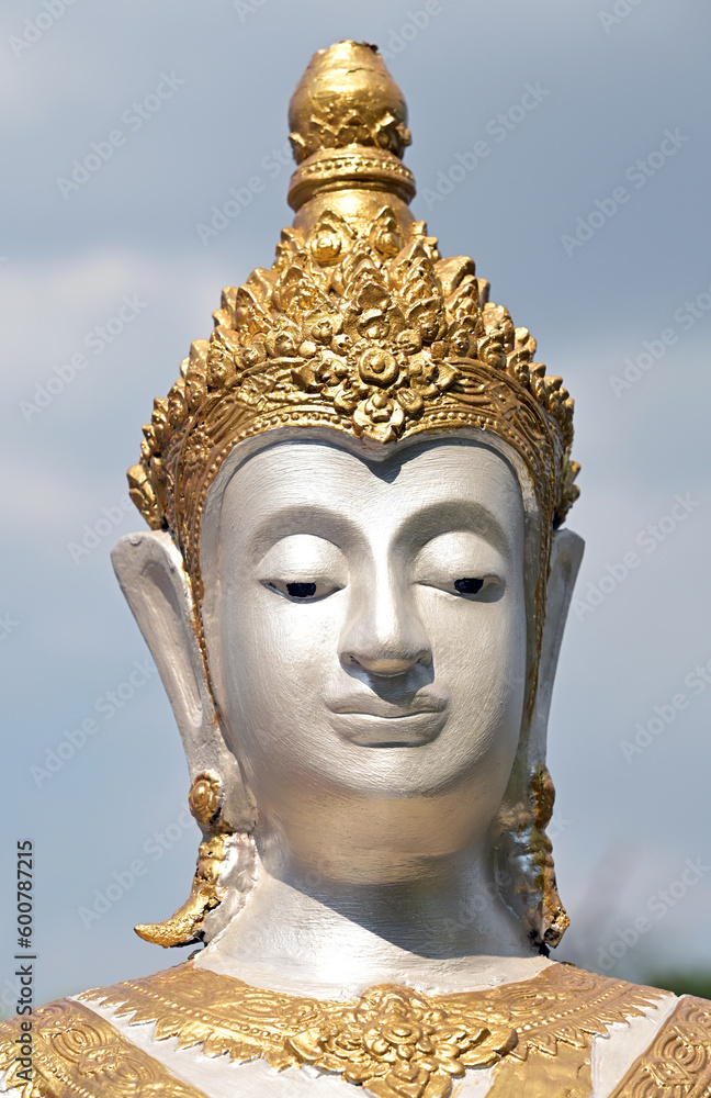 A statue of a white deity dressed in gold in a Buddhist temple.