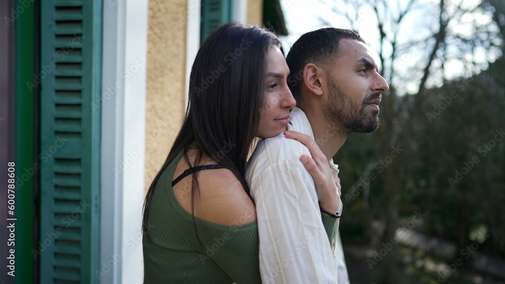 Girlfriend embracing boyfriend from behind while standing outside at home balcony. A loving Middle Eastern couple showing love and support while contemplating nature Girlfriend embracing boyfriend from behind while standing outside at home balcony. A loving Middle Eastern couple showing love and support while contemplating nature