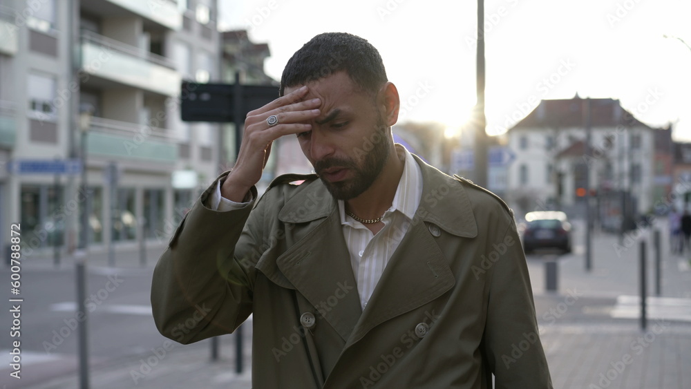 Frustrated young man walking in city street feeling disbelief. One Male Middle Eastern person walks in sidewalk suffering from regret and anxiety Frustrated young man walking in city street feeling disbelief. One Male Middle Eastern person walks in sidewalk suffering from regret and anxiety