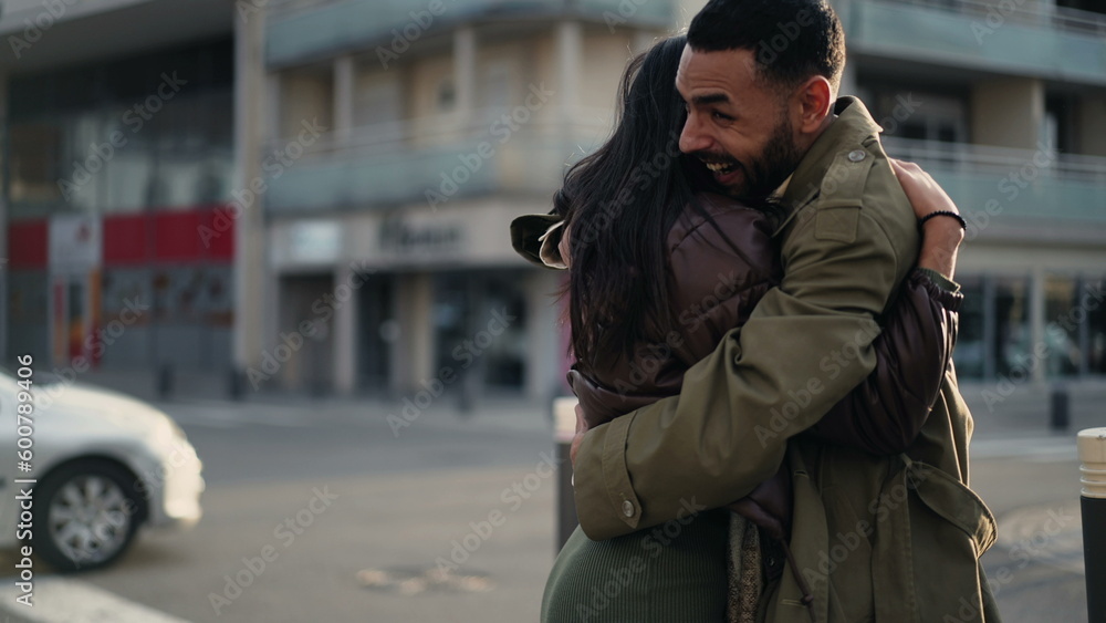 Fototapeta premium Happy genuine reunion_ Two people embracing in street feeling ecstatic. Authentic hug standing outdoors in urban environment