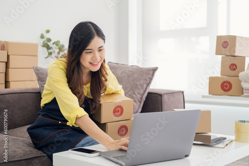 Small business owner packing in the cardbox at home office. Woman preparing a parcel for delivery at online selling business office. Entrepreneurs Arranging Goods With Parcel Boxes Startup Ideas. © Fahng