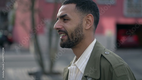 A content Arab man strolls down city. Tracking shot of a thoughtful Middle Eastern male wearing a jacket portrait face closeup in motion