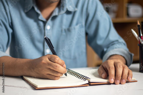 Male hand writing a note in a notebook concept of business people working
