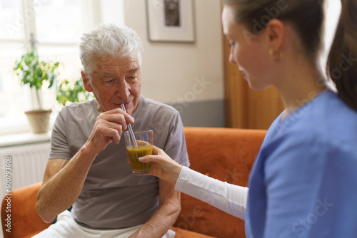 Nurse giving fruit juice to a senior man. photo