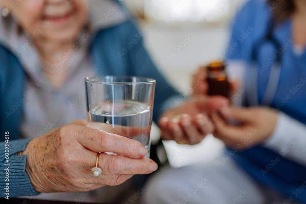 Close-up of nurse giving medicine to senior woman at her home. Close-up of nurse giving medicine to senior woman at her home.