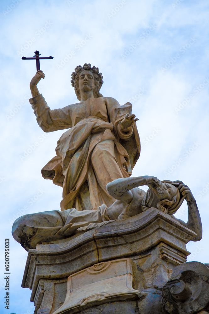 Statue of a saint with cross stepping on a human