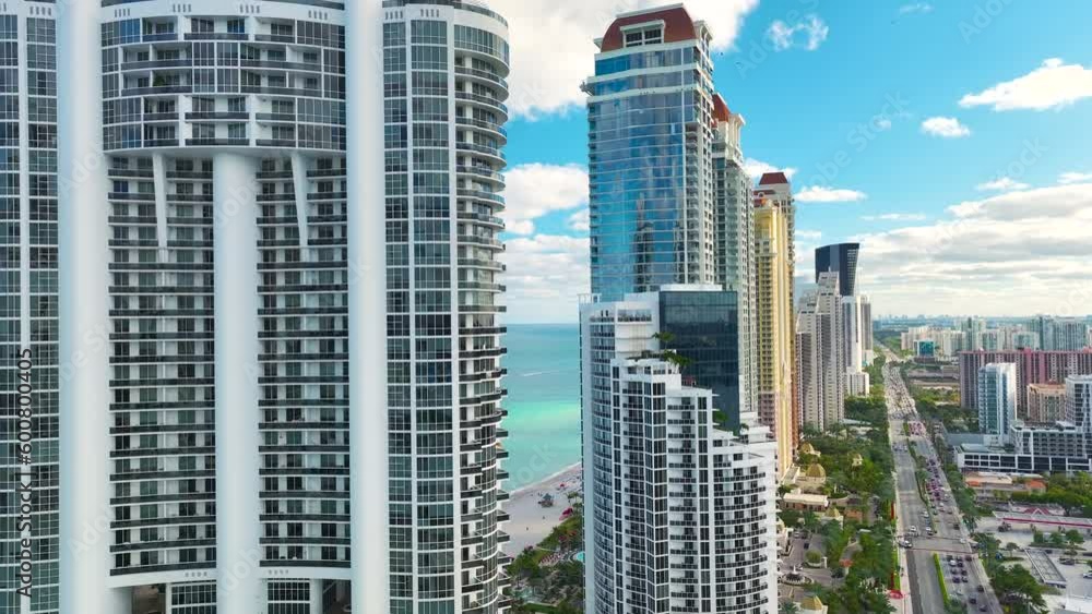 Expensive highrise hotels and condos on Atlantic ocean shore in Sunny Isles Beach city and busy street traffic. American tourism infrastructure in southern Florida