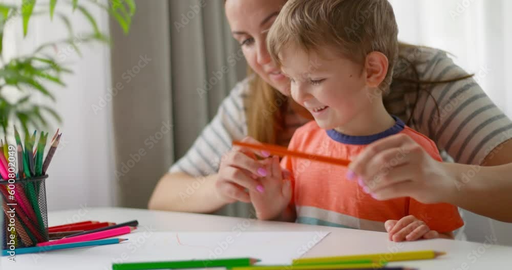 Mother and child drawing with pencils sitting at the desk at home. Happy family Mother and child drawing with pencils sitting at the desk at home. Happy family