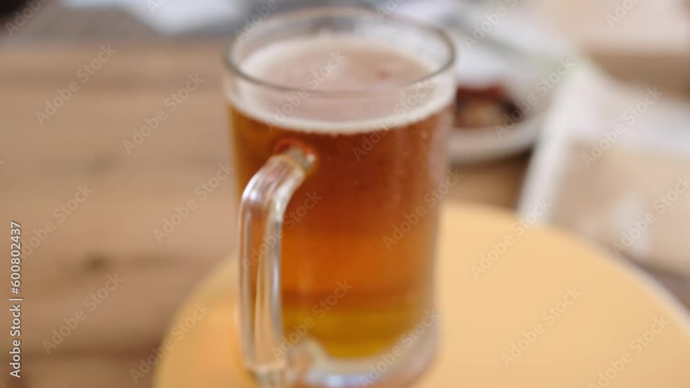 Close-up glass of cold beer on the table. Glass full light craft beer spin with drop of condensation cold drink. Cold alcohol beer drink in mug. Drink glass on table. Close-up glass of cold beer on the table. Glass full light craft beer spin with drop of condensation cold drink. Cold alcohol beer drink in mug. Drink glass on table.