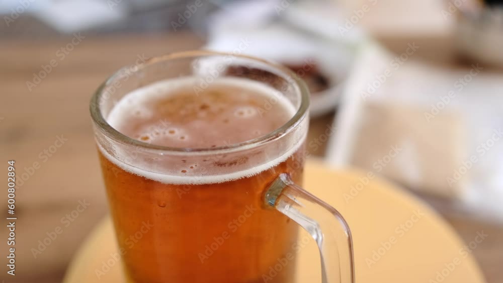 Close-up glass of cold beer on the table. Glass full light craft beer spin with drop of condensation cold drink. Cold alcohol beer drink in mug. Drink glass on table. Close-up glass of cold beer on the table. Glass full light craft beer spin with drop of condensation cold drink. Cold alcohol beer drink in mug. Drink glass on table.