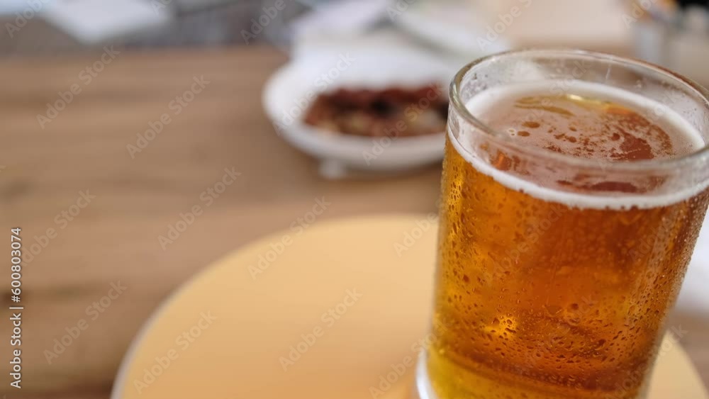 Close-up glass of cold beer on the table with snacks. Glass full light craft beer spin with drop of condensation cold drink. Cold drink glass on table. Cold alcohol stout beer drink in mug. Close-up glass of cold beer on the table with snacks. Glass full light craft beer spin with drop of condensation cold drink. Cold drink glass on table. Cold alcohol stout beer drink in mug.
