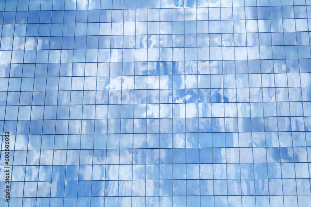 Glass building detail reflecting the fluffy clouds in the blue sky - background Glass building detail reflecting the fluffy clouds in the blue sky - background