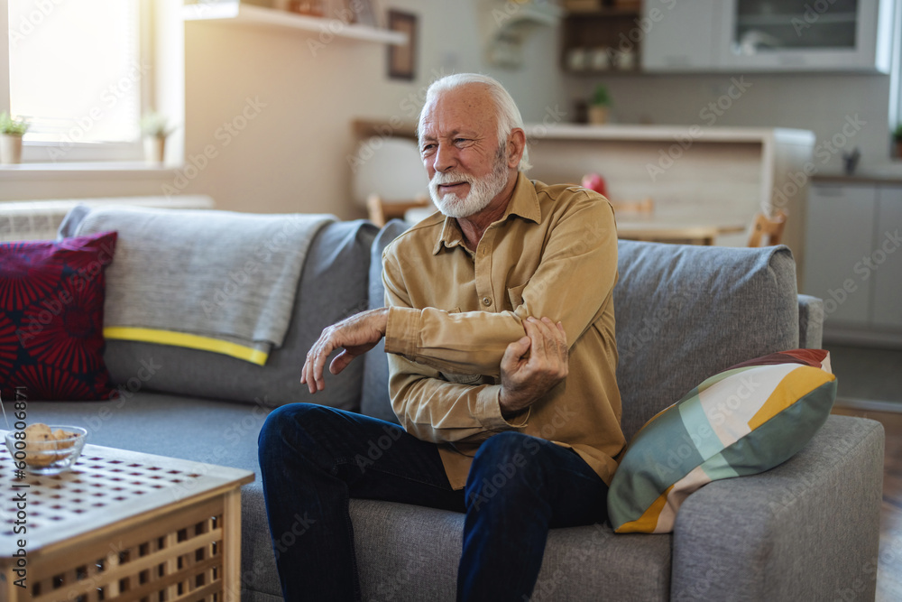 People, healthcare and problem concept - unhappy senior man suffering from elbow pain at home. People, healthcare and problem concept - unhappy senior man suffering from elbow pain at home.