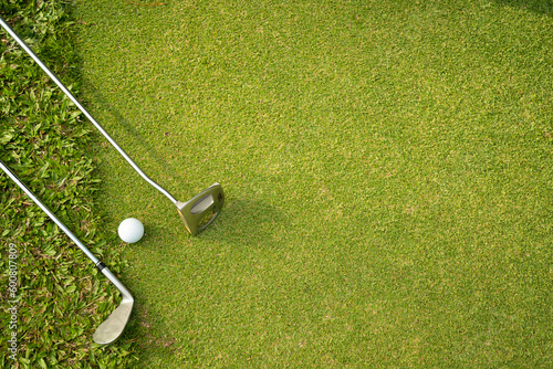 Golf ball and golf club on green in the evening golf course.