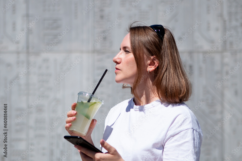 young woman drinking mojito and talking on the phone in summer in the city young woman drinking mojito and talking on the phone in summer in the city
