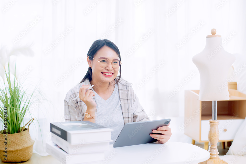 Asian woman enjoying designing clothes which is a job that she happily loves Asian woman enjoying designing clothes which is a job that she happily loves