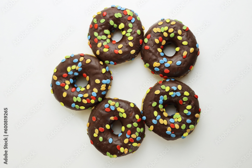 A set of doughnuts glazed with chocolate and colorful smarties. Five donuts isolated on a white background. Side view. Copy space A set of doughnuts glazed with chocolate and colorful smarties. Five donuts isolated on a white background. Side view. Copy space