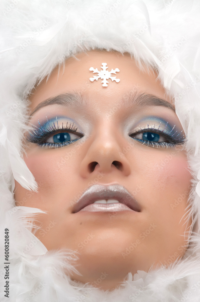 Girl with beautiful make up, white feathers and snow flake