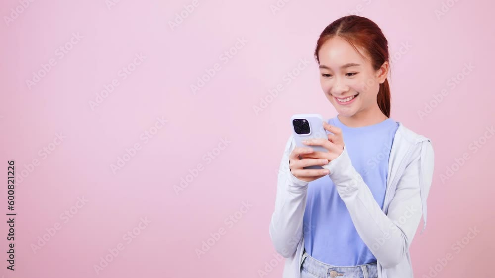 Smiling Asian woman in casual clothes looking at smartphone app using mobile phone.