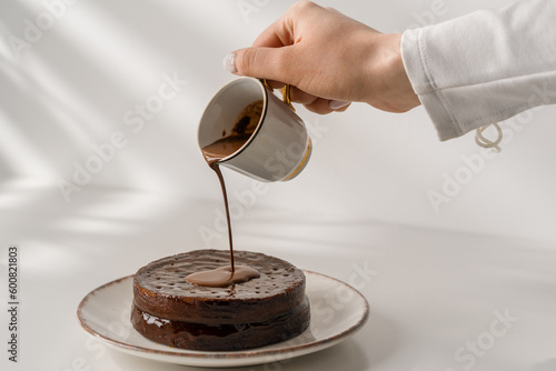 delicious freshly made chocolate sacher cake on a plate on a white background drizzled with hot chocolate dessert concept photo