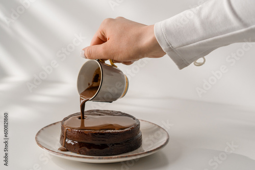 delicious freshly made chocolate sacher cake on a plate on a white background drizzled with hot chocolate dessert concept