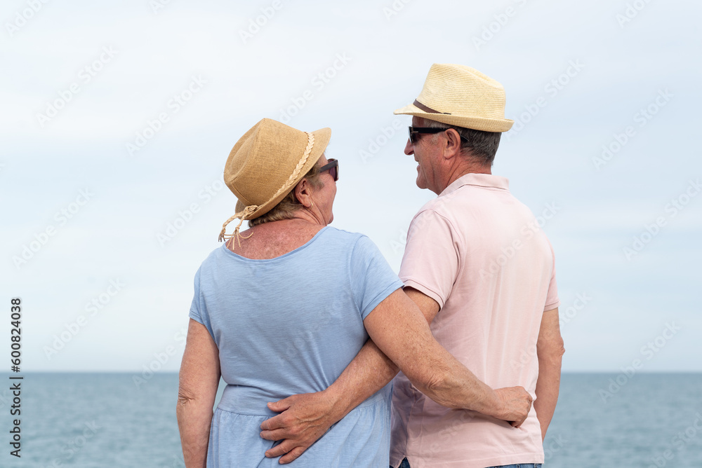 Rear view of a senior couple  looking each other with the sea on the background.