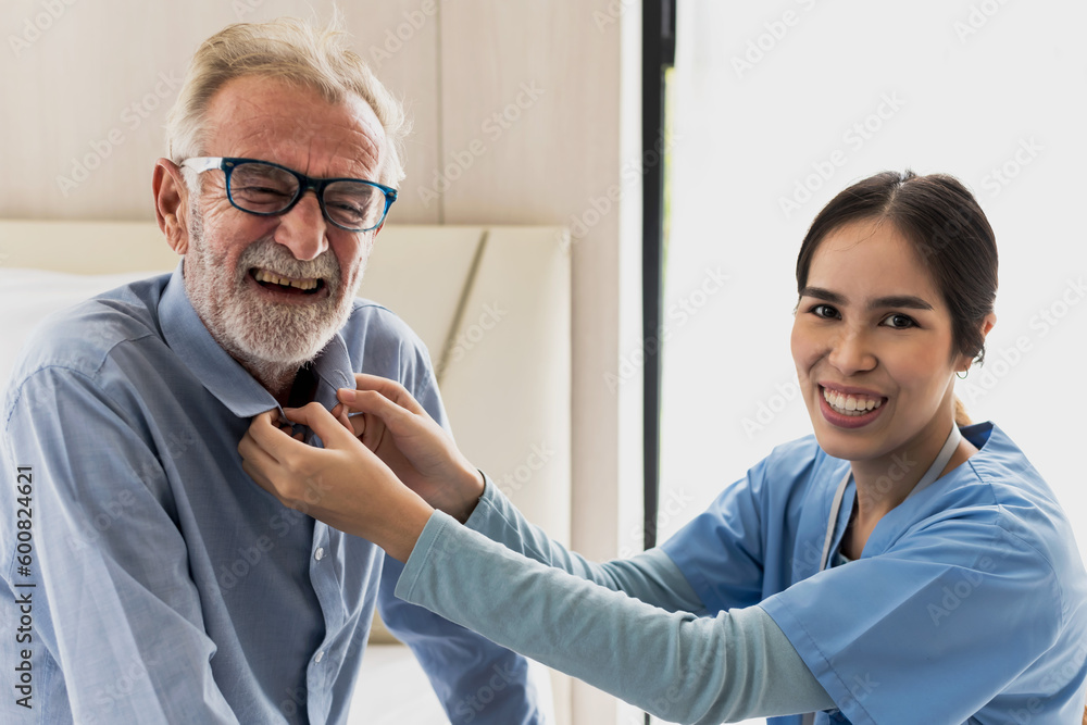 Friendly care taker woman helping elder man wearing shirt in Senior Care Friendly care taker woman helping elder man wearing shirt in Senior Care