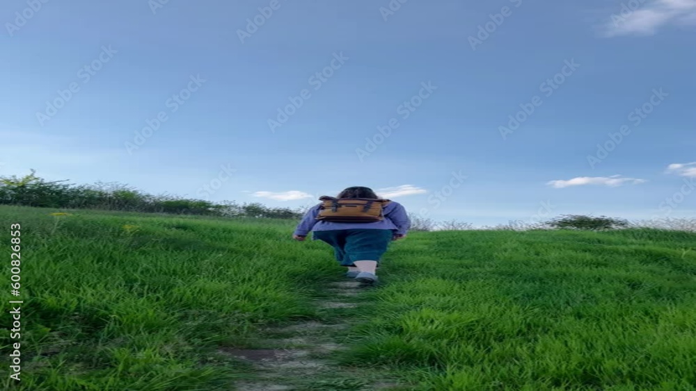 Woman in linen outfit and backpack hiking up a hill Woman in linen outfit and backpack hiking up a hill